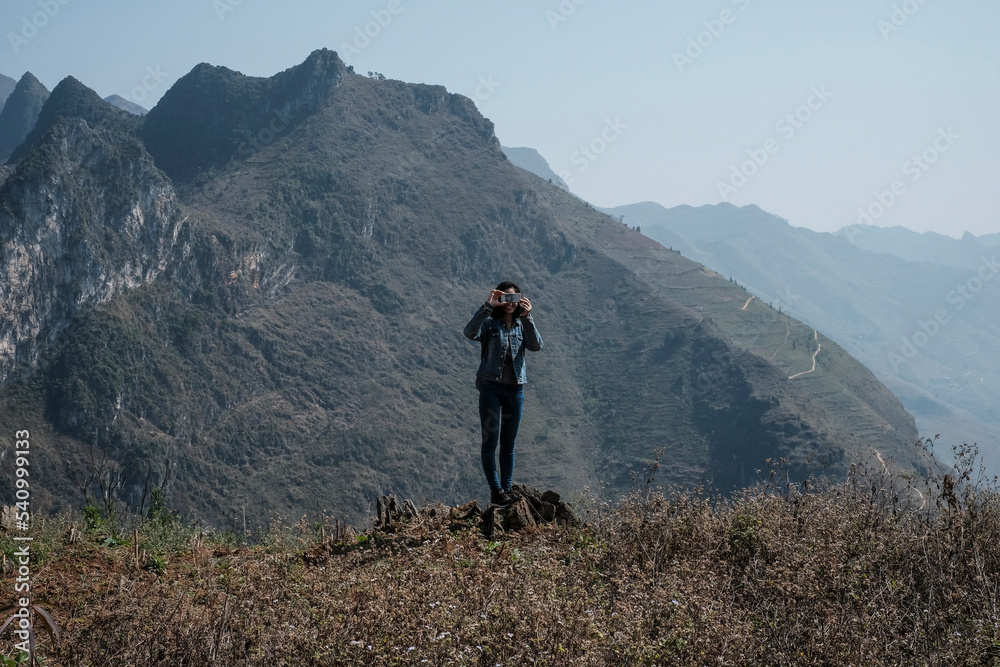 Woman photographing while standing against mountains Woman photographing while standing against mountains
