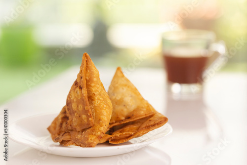 Plate of hot Samosas and cup of tea on table 