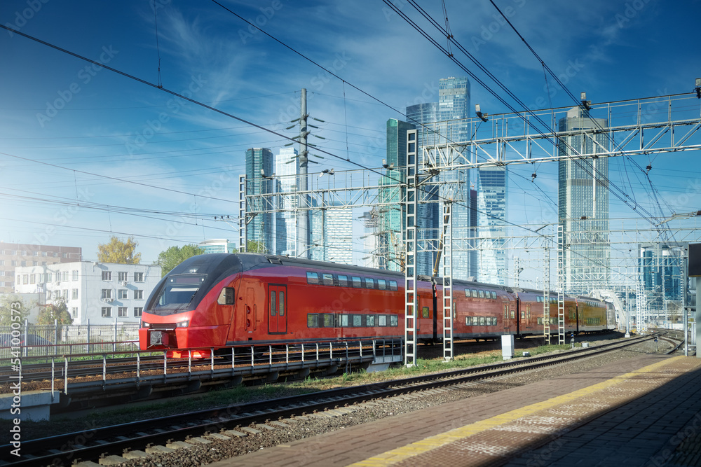 City train drive on railroad. Skyscrapers at downtown district on the background. Blue sky in sunny day. Transportation background