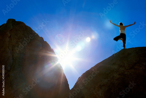 Woman doing yoga on boulder, Tree Pose.