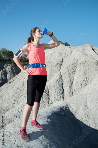 Woman in sportswear drinking water after running in mountains, Gurb, Barcelona, Catalonia, Spain photo