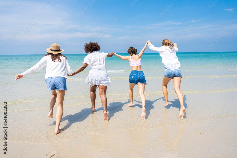 Photo of a group of girls of different ethnicities running and having fun together at the beach. on a fresh day