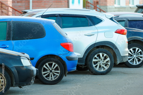 Close-up of the back of a frozen frosted blue car with other cars parked in a parking lot on a city street.Rest stoр.