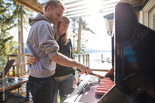 Young couple barbecuing at lakeside cabin, Kamloops, British Columbia, Canada photo