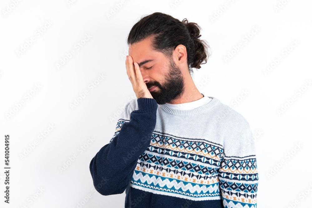 young bearded hispanic man wearing knitted sweater over white background with sad expression covering face with hands while crying. Depression concept. young bearded hispanic man wearing knitted sweater over white background with sad expression covering face with hands while crying. Depression concept.