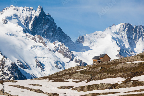 A hiker looks towards La Meije and the Massif des Ã‰crins from the Refuge du GolÃ©on, Hautes-Alpes, France. photo