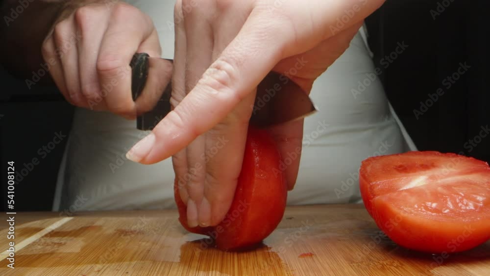 A girl cuts a peeled tomato into cubes for lasagna, close-up. A girl cuts a peeled tomato into cubes for lasagna, close-up.