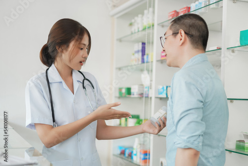 Medicine and health concept, Female pharmacist hold pill bottle to explaining medication for client