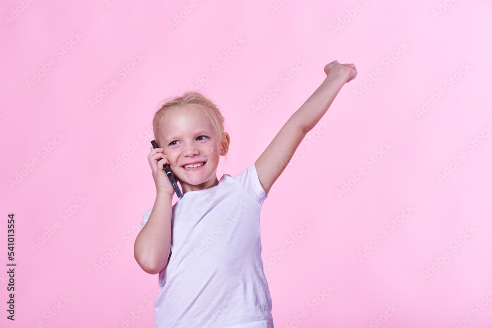 Excited little girl getting great, winning news over her phone; pink studio background Excited little girl getting great, winning news over her phone; pink studio background