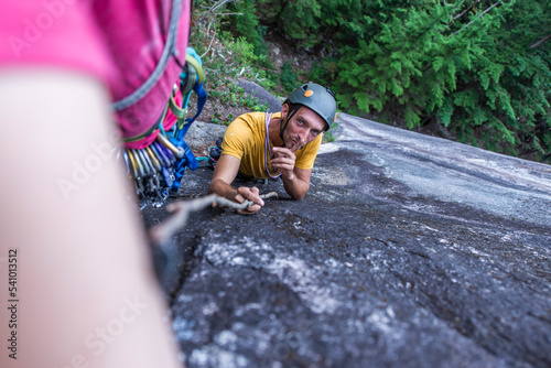 Man showing to shush and silence while poking climber with wood stick photo