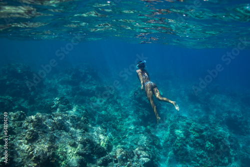 Female swims underwater in blue Hawaiian waters photo