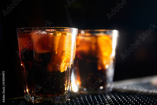 Alcoholic cocktails with ice and lemon slices on the bar on a dark background