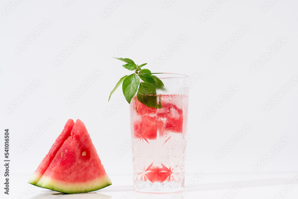 Vaso de zumo de sandía con trozos de sandia y hielo sobre fondo claro Vaso de zumo de sandía con trozos de sandia y hielo sobre fondo claro