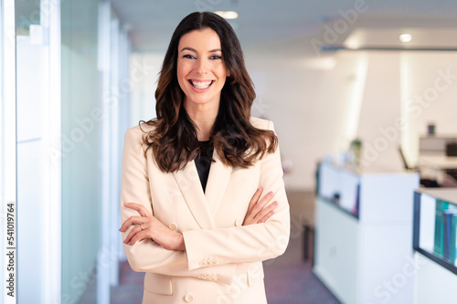 Brunette haired businesswoman looking at camera and smiling while standing at the office Free Download Brunette haired businesswoman looking at camera and smiling while standing at the office - GFXLoad