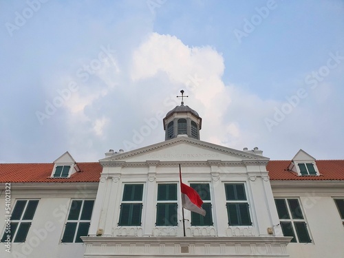 a historical building from dutch colonization era. old building with indonesian flag and blue sky photo