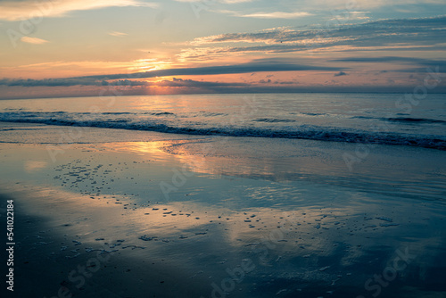 Sunrise on the beach with the sky reflecting on the wet sand © Alex P