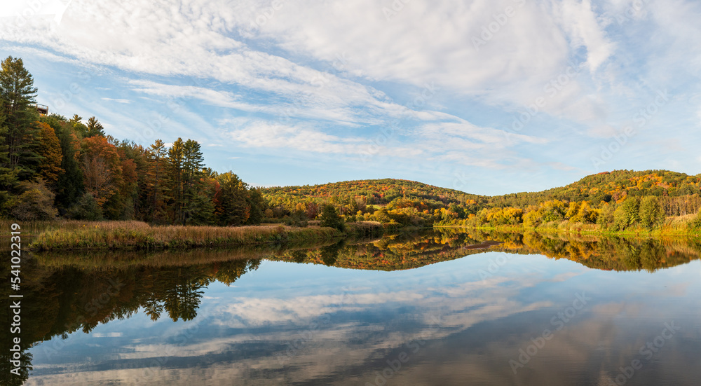 Calm and wide Ottauquechee river flows towards Quechee Gorge in Vermont with fall colors