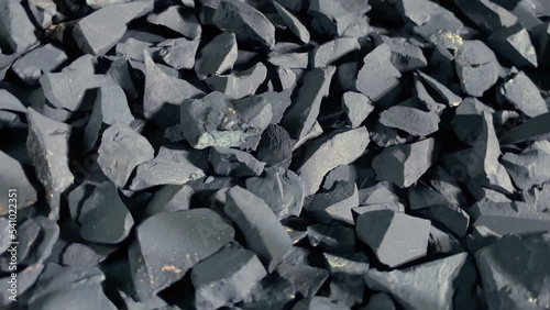 Coal or shungite stones rotating on black background. Selective focus photo