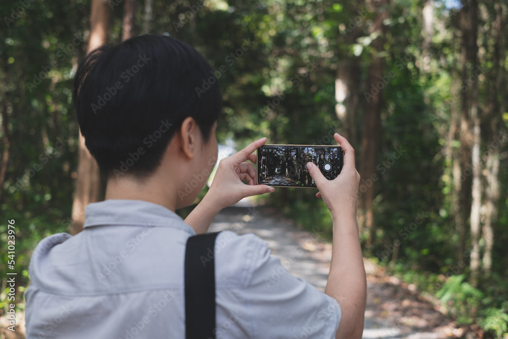A traveler is taking photo of nature trail by Mobile phone, smart phone. Concept of capture the environment, memory of journey and traveler. Spending time amoung nature. focus on hand with copy space A traveler is taking photo of nature trail by Mobile phone, smart phone. Concept of capture the environment, memory of journey and traveler. Spending time amoung nature. focus on hand with copy space