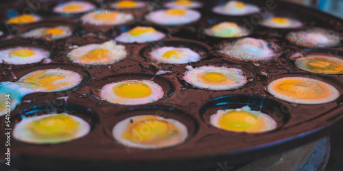 Close up look of quail eggd menu on a heat pan. Asian Thai street food. Concept of protein menu, nutrition and reginal local food. White and yellow background. Healthy popular food in Thailand.