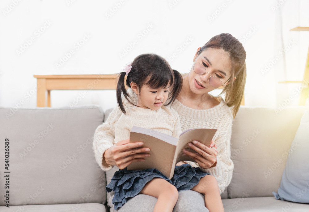 Light and blur people, Asian children and her mother reading a book, they sitting on sofa, happiness in family time, child learning and development Light and blur people, Asian children and her mother reading a book, they sitting on sofa, happiness in family time, child learning and development