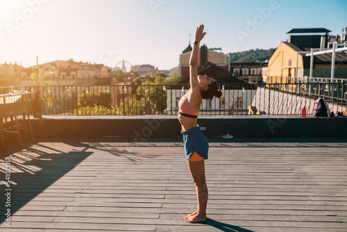 Young woman practicing yoga on the roof of a building © teksomolika