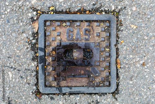 metal cover of a gas pipeline on a street with the word gas