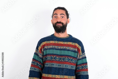 Stunned Caucasian man with beard wearing sweater over white background stares reacts on shocking news. Astonished man holds breath