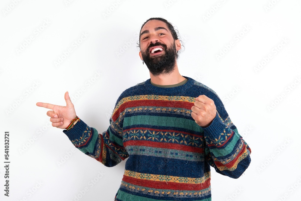 Naklejka premium Cheerful Caucasian man with beard wearing sweater over white background showing copy space ad celebrating luck