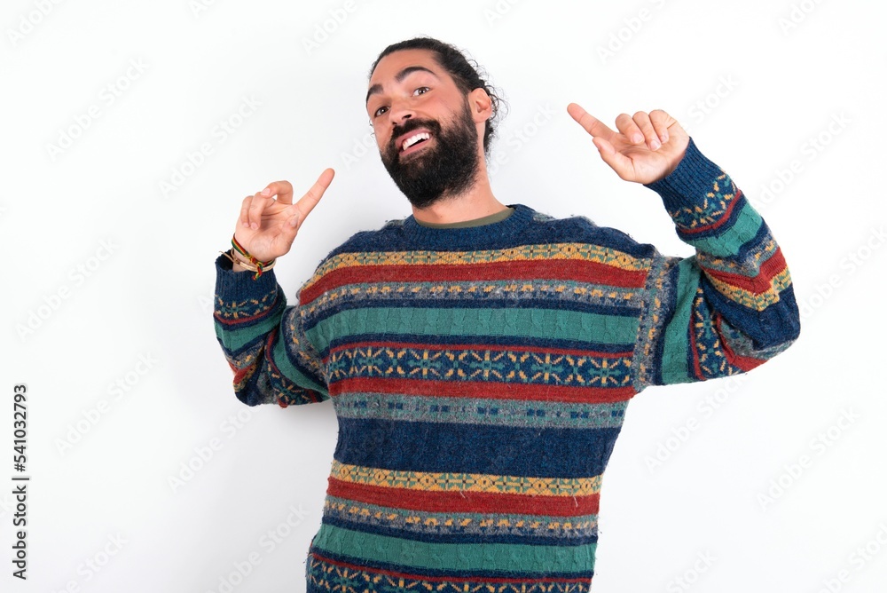 Naklejka premium Cheerful Caucasian man with beard wearing sweater over white background demonstrating hairdo