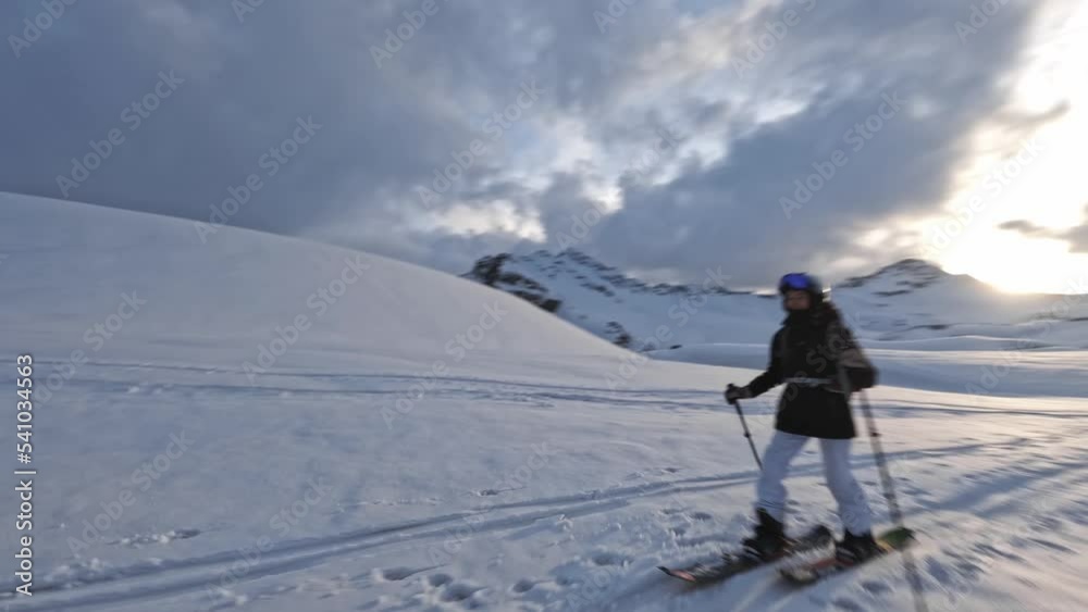 Aerial view woman going to skitour on snow trace at ski tour winter hiking leisure activity sunset mountain scenery. FPV drone shot athlete enjoy extreme trekking with sticks cliff frost landscape 4k Aerial view woman going to skitour on snow trace at ski tour winter hiking leisure activity sunset mountain scenery. FPV drone shot athlete enjoy extreme trekking with sticks cliff frost landscape 4k