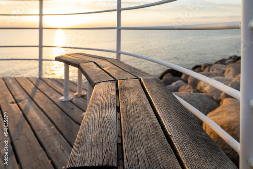 Wooden bench by the sea at sunset