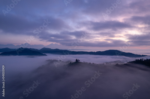 Cerkev Sveti Tomaž (St. Thomas Church) near Škofja Loka, Slovenia. Foggy morning and sunrise, drone photo