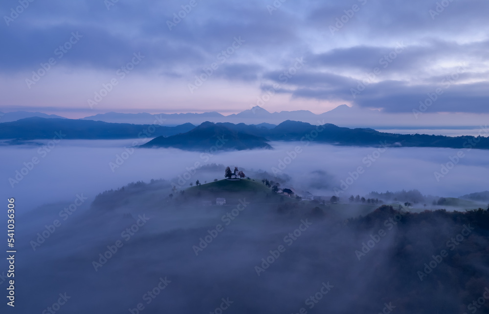 Cerkev Sveti Tomaž (St. Thomas Church) near Škofja Loka, Slovenia. Foggy morning and sunrise, drone photo Cerkev Sveti Tomaž (St. Thomas Church) near Škofja Loka, Slovenia. Foggy morning and sunrise, drone photo