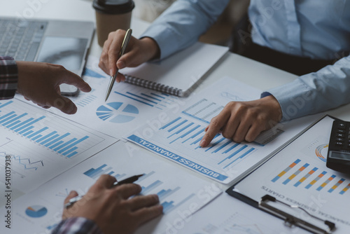 Financial analysts analyze business financial reports on a calculator planning investment project during a discussion at a meeting of corporate showing the results of their successful teamwork. 