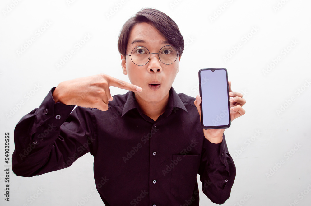 excited young asian man showing phone screen with happy euphoric shocked wow expression. man pointing to screen phone with thumb up. billboard model advertisment concept. excited young asian man showing phone screen with happy euphoric shocked wow expression. man pointing to screen phone with thumb up. billboard model advertisment concept.