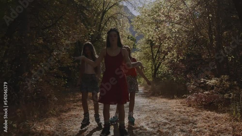 Carefree girls inline skating and listening to headphones on park path in autumn / American Fork Canyon, Utah, United States photo