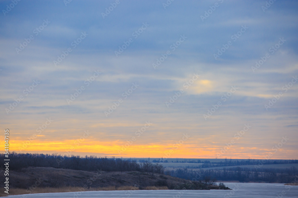 Landscape at dawn of a frozen river . Winter landscape on a frosty morning of a steppe river