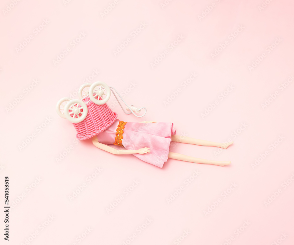 A woman lies down with a pink shopping cart over her head. Pink background. A woman lies down with a pink shopping cart over her head. Pink background.