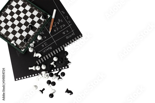 Magnetic chess board and chess pieces on a transparent background. A notebook with notes of chess moves. International Chess Day. Copy space