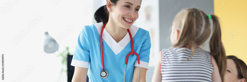 Φωτογραφία Pretty pediatrician chatting with cute patient child girl on appointment in clin