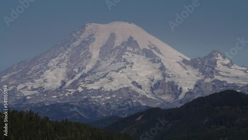 Tilt up to snow on mountain range under blue sky / Packwood, Washington, United States photo