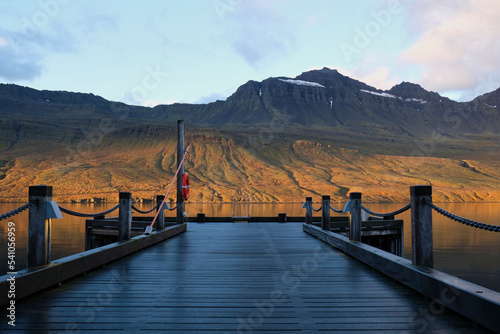 View from the Fáskrúðsfjörður dock located in the eastern fjords of Iceland. Landscape shot at sunrise with the mountains in the background.