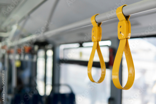 Row of yellow grab safety straps handles inside shuttle bus, selective focus