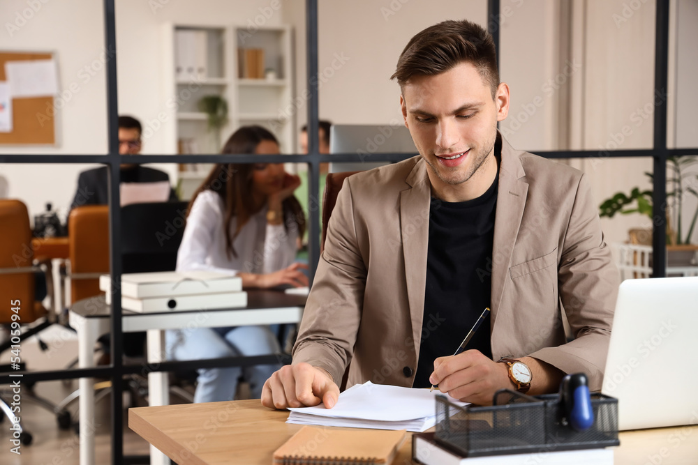Young businessman with documents working at table in office Young businessman with documents working at table in office