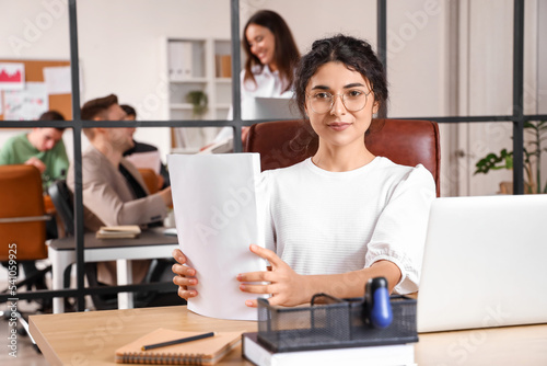 Young businesswoman with documents working at table in office