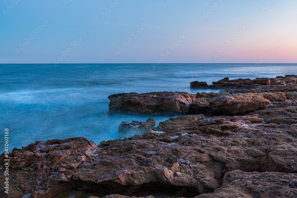 Blue Sunrise at the beach covered in rocks
