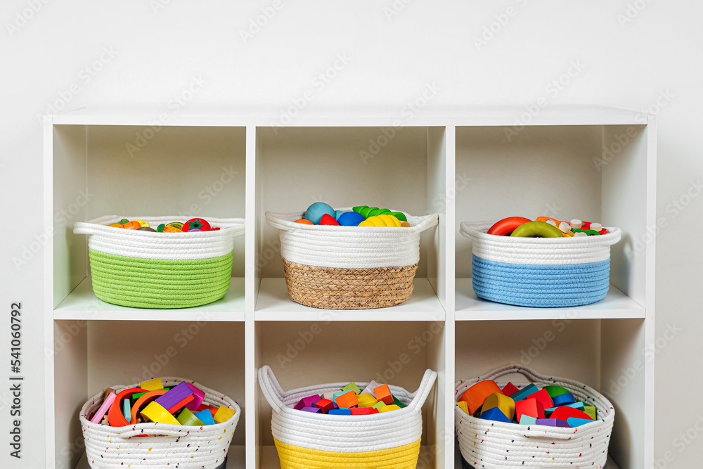 Colorful storage baskets on shelves. White shelving with rainbow wooden toys in cloth stylish