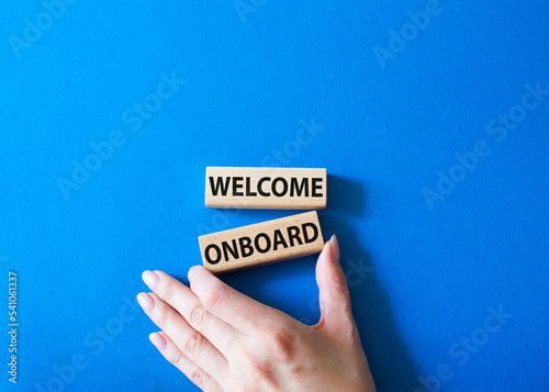 Welcome onboard symbol. Concept words Welcome onboard on wooden blocks. Beautiful blue background. Businessman hand. Business and Welcome onboard concept. Copy space.