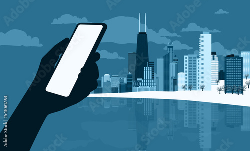 Εκτύπωση καμβά The silhouette of a human hand using a mobile phone against the backdrop of a modern western winter cityscape